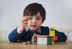 A cild playing with money and toy houses.