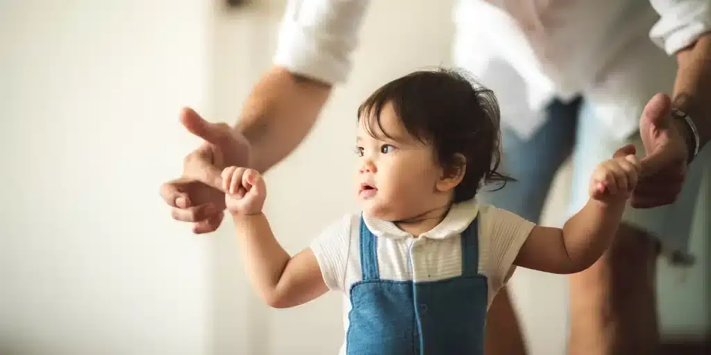 A child holding on to parents hands.