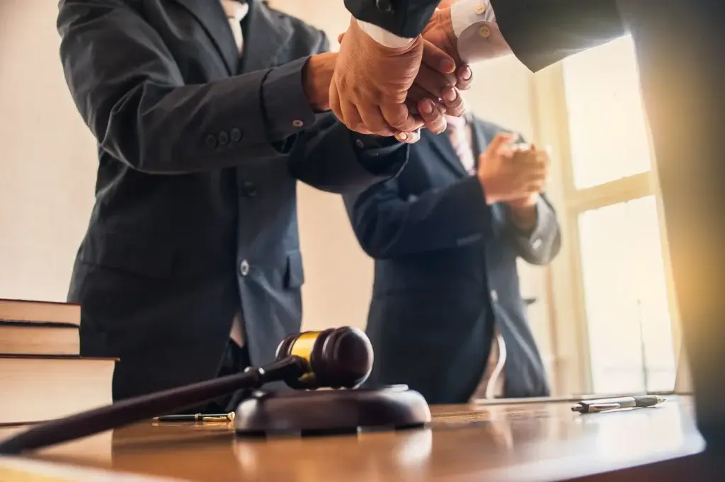 Attorneys shake hands and acknowledge progress across a table with a gavel present, symbolizing successful resolution of post-divorce disputes and the potential for courtroom enforcement of divorce agreements in Texas.